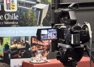 Una cámara Sony, sobre un trípode, apunta hacia el pendón de la Universidad Austral de Chile (UACh) que cubre el fondo de la actividad.
